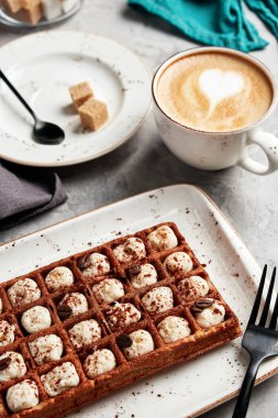 Gri arka planı kahveyle dolduran büyük waffle 'lar.