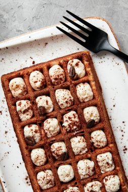 Gri arka planı kahveyle dolduran büyük waffle 'lar.