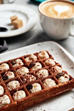 Gri arka planı kahveyle dolduran büyük waffle 'lar.