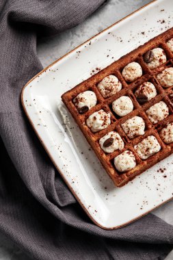 Gri arka planı kahveyle dolduran büyük waffle 'lar.