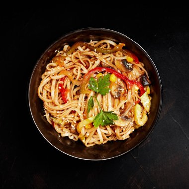 Sebzeli ramen ve susam tohumları siyah arka plan manzaralı bir tabakta.