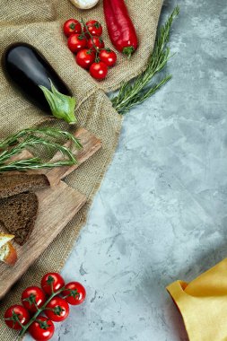 Çuval ekmeği, domates, yeşillik ve patlıcanla açık gri beton arka plan