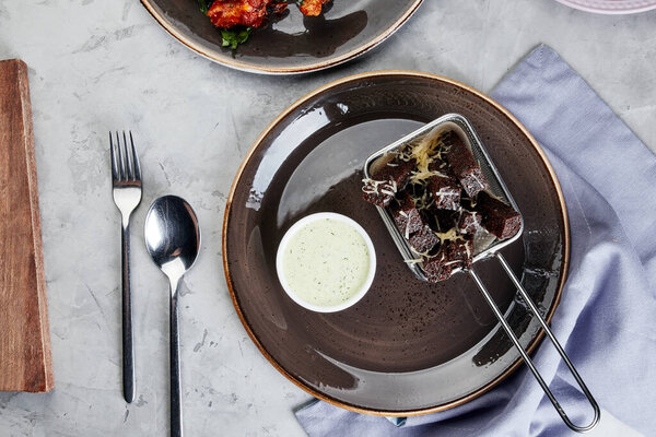 жареные гренки с чесноком и соусом на тарелке на сером бетонном фоне