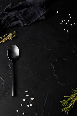 Siyah çatal kaşığı, bıçağı ve peçetesi olan siyah desenli bir arka plan.