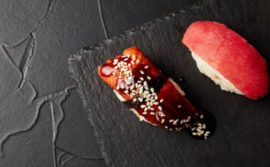 Siyah desenli arka plan görünümlü ahşap bir tahtada suşi.