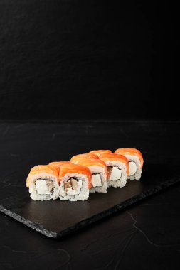 Kara desenli arkaplanda siyah bir tahta üzerinde yuvarlanıyor