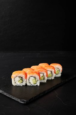 Kara desenli arkaplanda siyah bir tahta üzerinde yuvarlanıyor