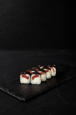 Kara desenli arkaplanda siyah bir tahta üzerinde yuvarlanıyor