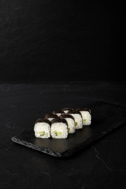 Kara desenli arkaplanda siyah bir tahta üzerinde yuvarlanıyor