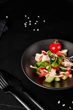 Sebzeli salata siyah desenli arka planda bir tabakta