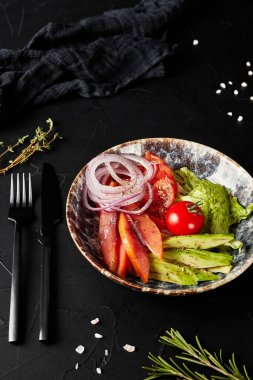 Sebzeli salata siyah desenli arka planda bir tabakta