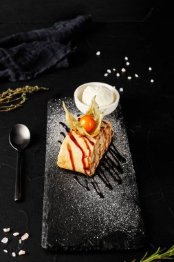 Karanlık bir arka planda kara tahtada fitalis ile tatlı rulo.