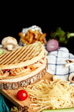 Kapalı pizza tahtanın üzerinde rendelenmiş peynir ve sebzelerle.