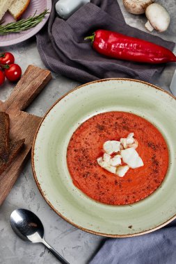 Erimiş peynirli domates çorbası gri beton arka planda bir tabakta