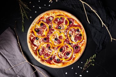 pizza siyah desenli arka planda koyu peçete ve altın dallar üst manzaralı