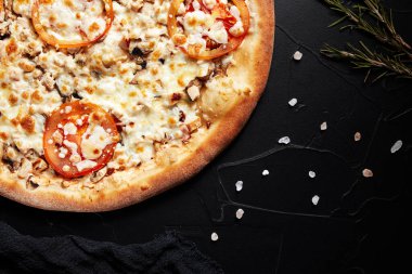 pizza siyah desenli arka planda koyu peçete ve altın dallar üst manzaralı