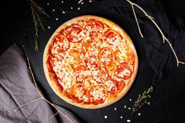 pizza siyah desenli arka planda koyu peçete ve altın dallar üst manzaralı