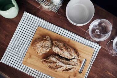 Tahta bir tahtanın üzerinde dilimlenmiş çavdar ekmeği. Tahta bir masanın üstünde kareli bir peçete.