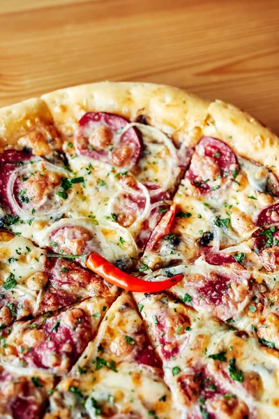 Tahta kahverengi bir masada, tabakta pizza.