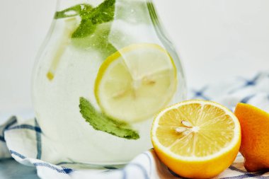 Hafif arka planda meyvelerin yanında mojito bulunan cam sürahi.
