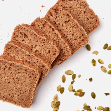 Beyaz bir tabakta dilimlenmiş çavdar ekmeği ve kabak çekirdeği. 