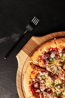 Siyah desenli arka plan görünümlü ahşap tabanlı pizza.