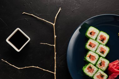 Siyah desenli arka planda mavi bir tabakta yeşil pirinç kağıdına sarılmış.