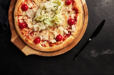 Siyah desenli arka plan görünümlü ahşap tabanlı pizza.