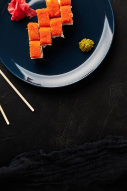 Siyah desenli arka planda mavi bir tabakta havyarda yuvarlanıyor.