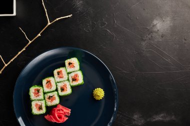 Siyah desenli arka planda mavi bir tabakta yeşil pirinç kağıdına sarılmış.