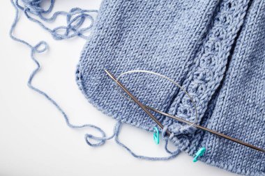 Beyaz arka planda örgü iğneleri üzerine mavi örülmüş ürün