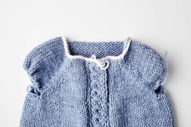 Beyaz arka planda örgü iğneleri üzerine mavi örülmüş ürün