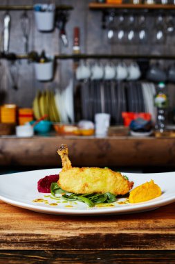 Mutfağın arka planında bir tabak Kiev pirzolası.