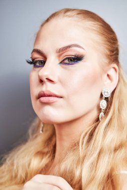 Gri arka planda parlak makyajlı güzel bir kız.