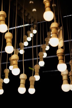 Kablodaki ampuller koyu bir arkaplanda asılı.