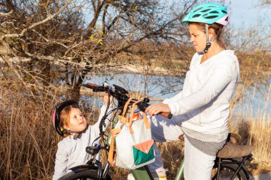 Gerçek Anne ve Kızı Güneşli Dağ manzarasında Bisiklete Biniyor