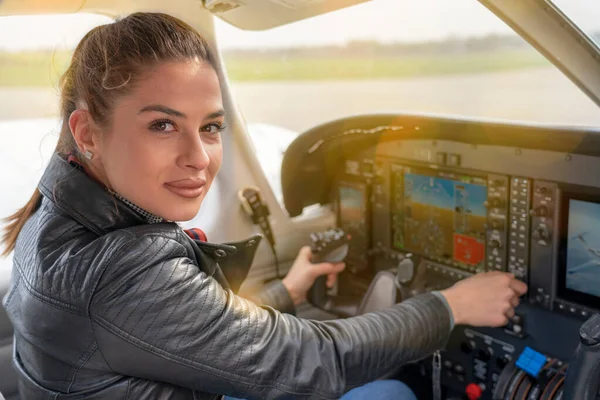 Beautiful Smiling Woman Pilot Sitting in Cabin of Modern Aircraft. Portrait of Female Pilot in the Light Aircraft Cockpit. Woman Looking at Camera from the Cockpit of a Private Plane.