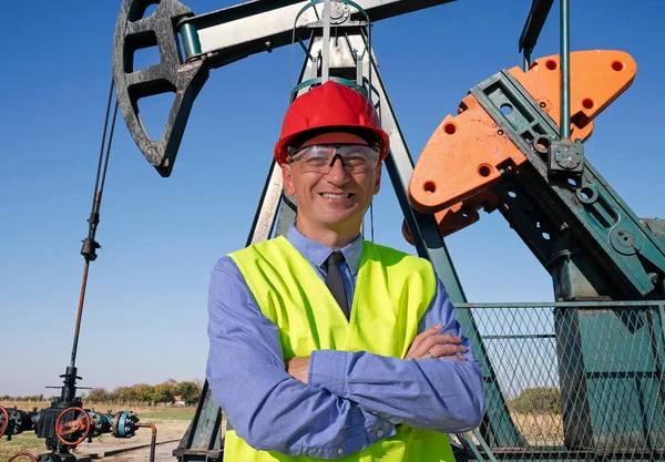 红色硬帽和黄色西部的石油和天然气工程师站在油井泵杰克前面 快乐的工人看着相机 石油工程师或商人的肖像 — 图库照片