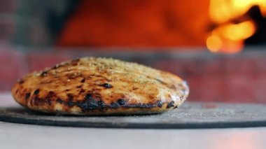 Wood Fired Brick Oven 'ın önünde Zeytinyağı Taze Fırınlanmış Çörek ile El Baharat ve Fırçalama. Arka planda yanan fırın ateşiyle ağız sulandıran sıcak çörek. Gıda Arkaplanı. 