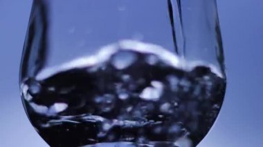 Mavi Arkaplan 'a Karşı İçme Suyu dökülüyor. İçme bardağına maden suyu dökülüyor..