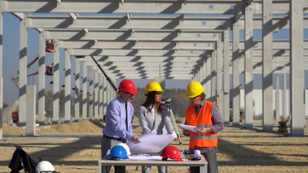 Equipe Construção Mista Hardhats Amarelos Vermelhos Discutir Sobre Blueprint Local — Vídeo de Stock