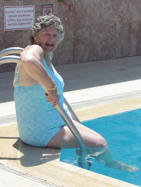 En gammal åldern pensionär får in en pool — Stockfoto