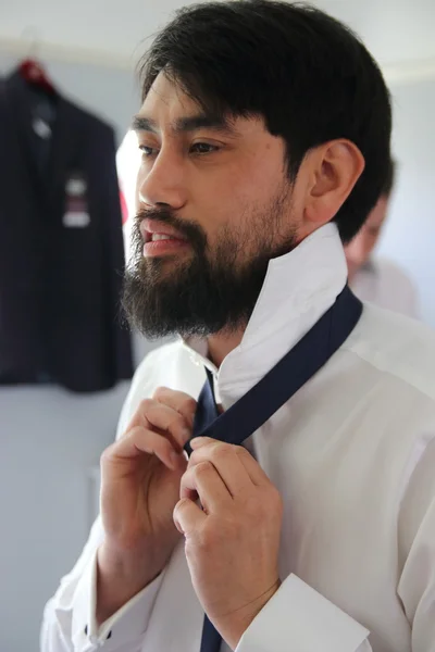 An asian man putting on a tie — Stock Photo, Image
