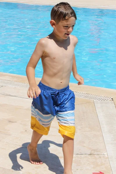 Un niño jugando junto a una piscina — Foto de Stock