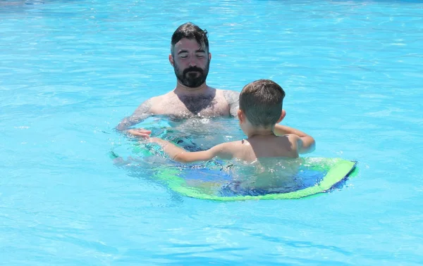 Um pai e um filho se divertindo em uma piscina — Fotografia de Stock