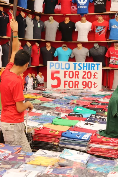 Camisas falsas a la venta en un puesto en un mercado local — Foto de Stock
