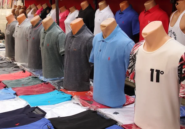 Camisas falsas a la venta en un puesto en un mercado local Imagen de archivo