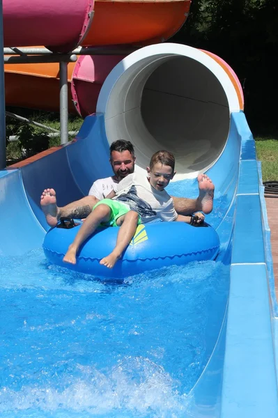 Un padre y un hijo se divierten en un tobogán acuático —  Fotos de Stock