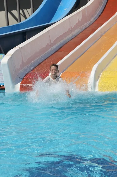 Um menino se divertindo em um escorrega de água — Fotografia de Stock