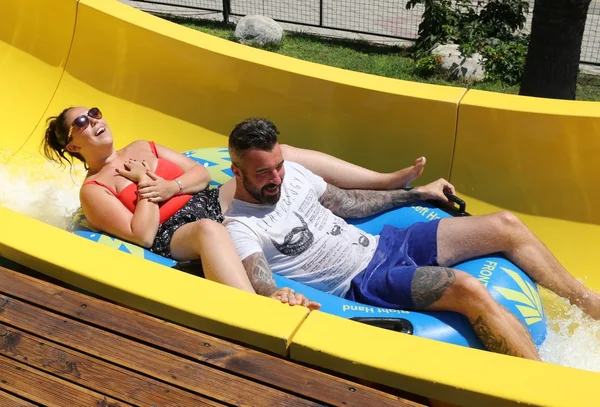 Um casal inglês se divertindo em um escorrega de água — Fotografia de Stock